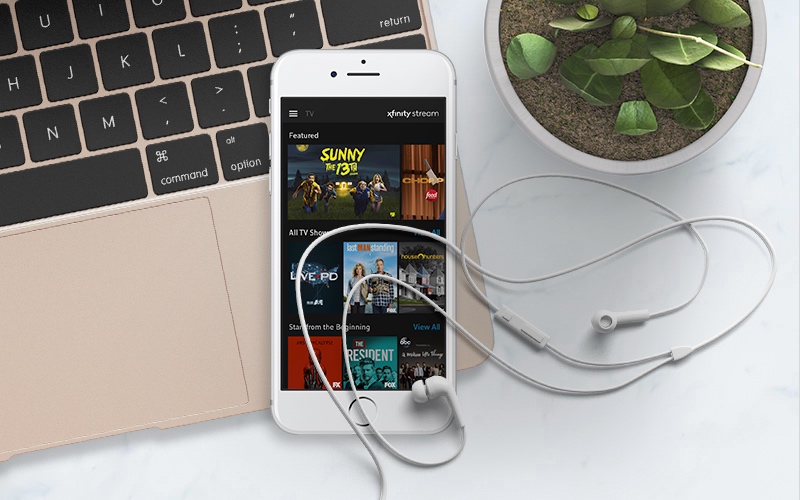 Mobile phone displaying TV shows with headphones on top of the phone